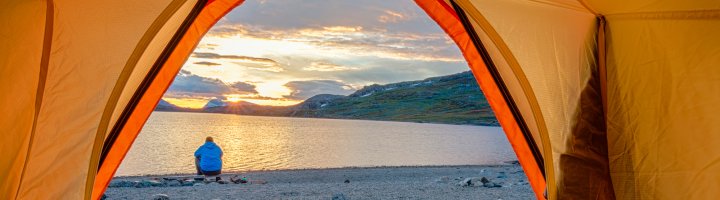 A backpacker rests near a mountain lake.