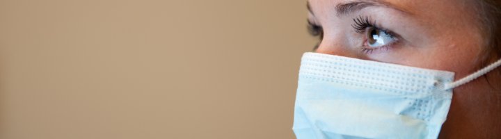 An acute care nurse wears a procedure mask.